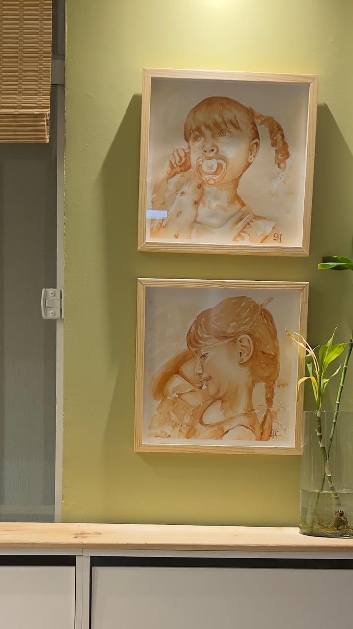 Dois retratos infantis em aquarela em parede verde